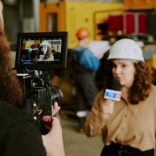 Journaliste en casque filmée dans usine industrielle