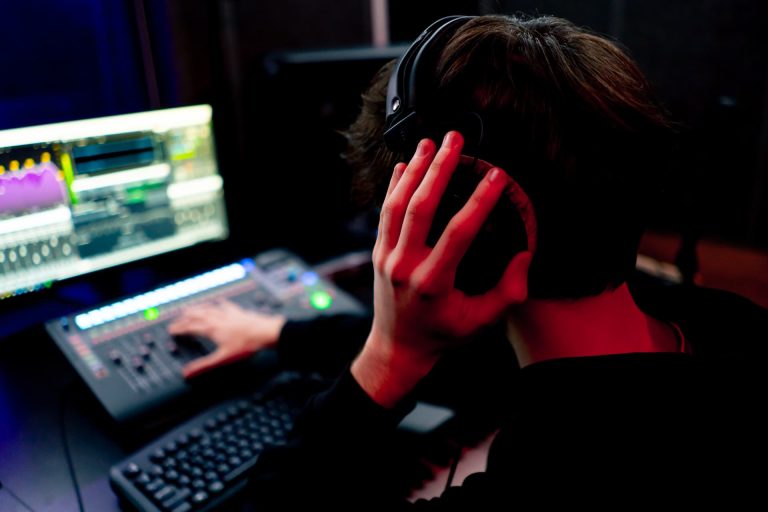 Technicien son au casque pendant l’enregistrement d’un comédien voix en studio